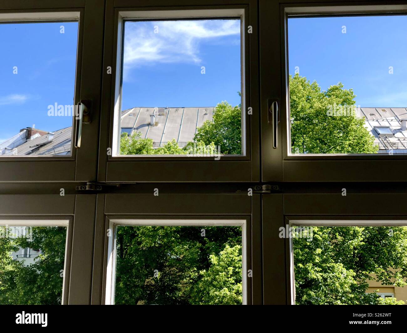 In prossimità di una finestra con vista sugli alberi e sul tetto di una casa Foto Stock