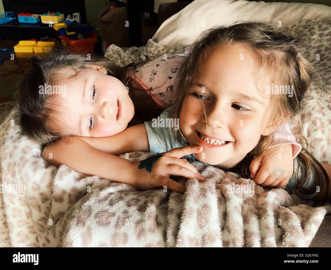 Felice sorelle coccole su una sedia con coperta - Immagine stock catturata con smartphone