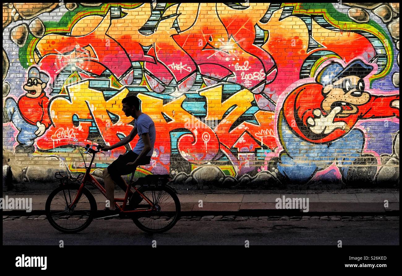 Un ciclista passa su un ampio e colorato sezione di arte di strada. Credito foto © COLIN HOSKINS. Foto Stock