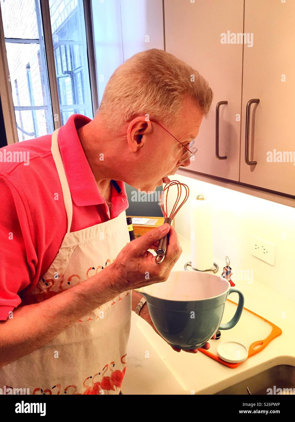 Brillantemente vestito uomo senior per la cottura in un appartamento cucina, STATI UNITI D'AMERICA - Immagine stock catturata con smartphone