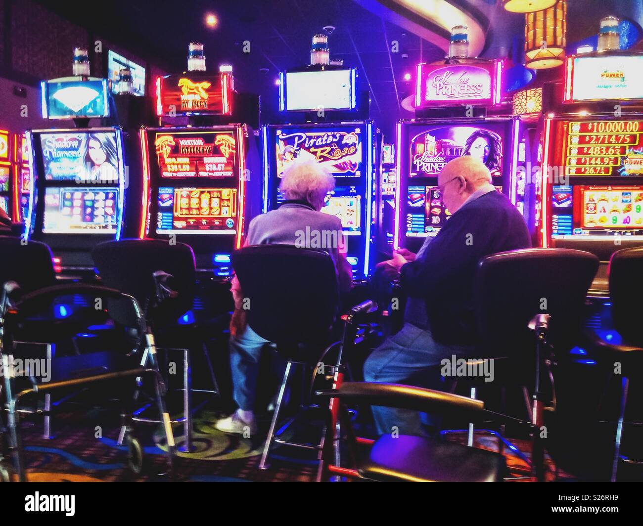 Due senior persone il gioco d'azzardo il loro denaro in macchine di scanalatura in un casinò, STATI UNITI D'AMERICA. Foto Stock