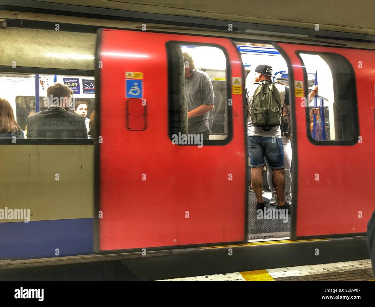 La metropolitana di Londra, le persone in una regione del nord della linea ferroviaria metropolitana, porte aperte, la stazione della metropolitana di Leicester Square, Londra, Inghilterra Foto Stock