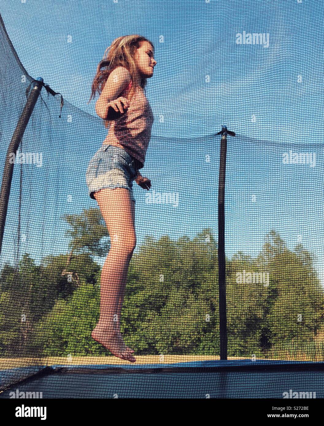 Tween girl saltando su un trampolino Foto Stock