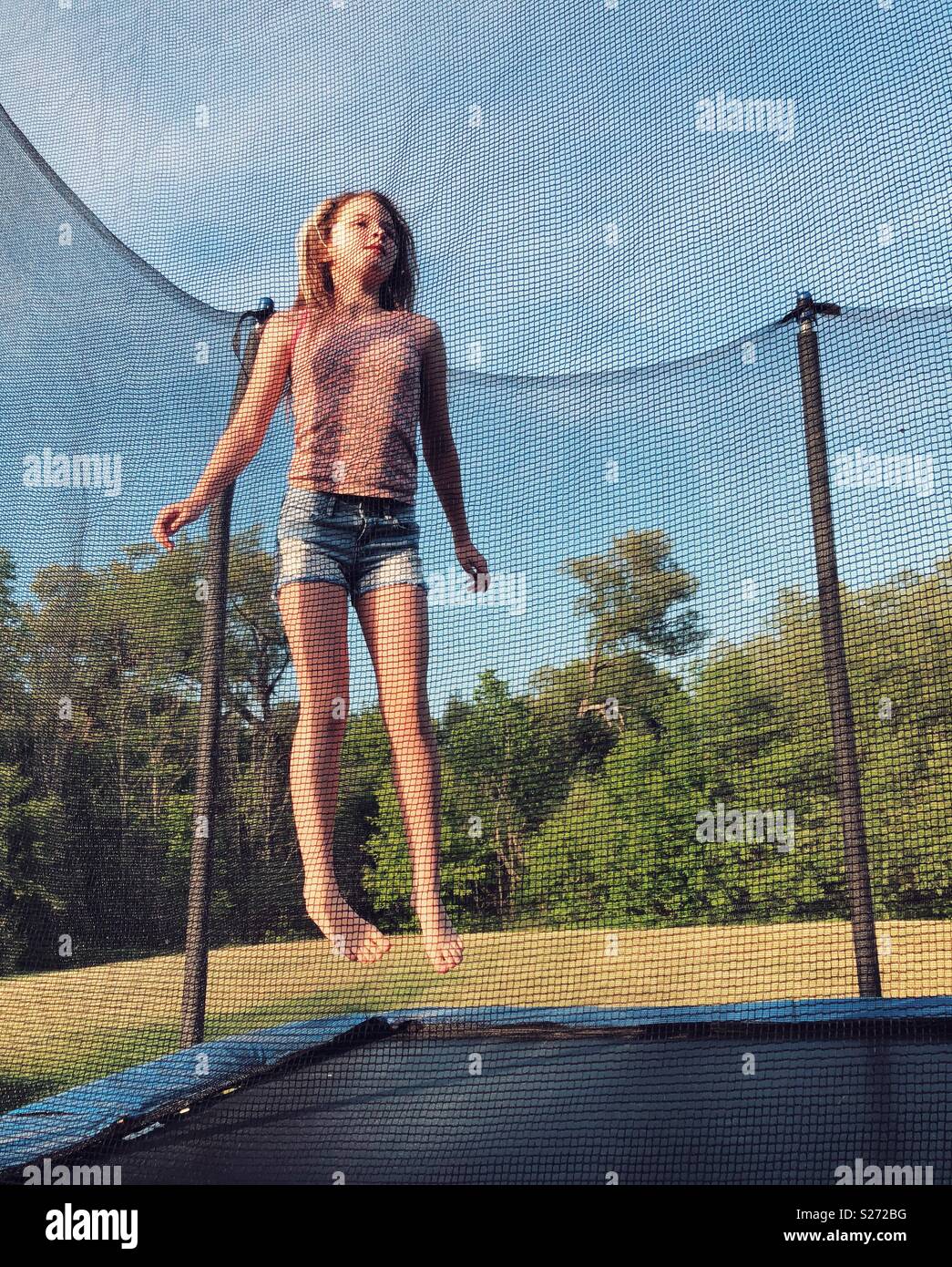Tween girl saltando su un trampolino Foto Stock