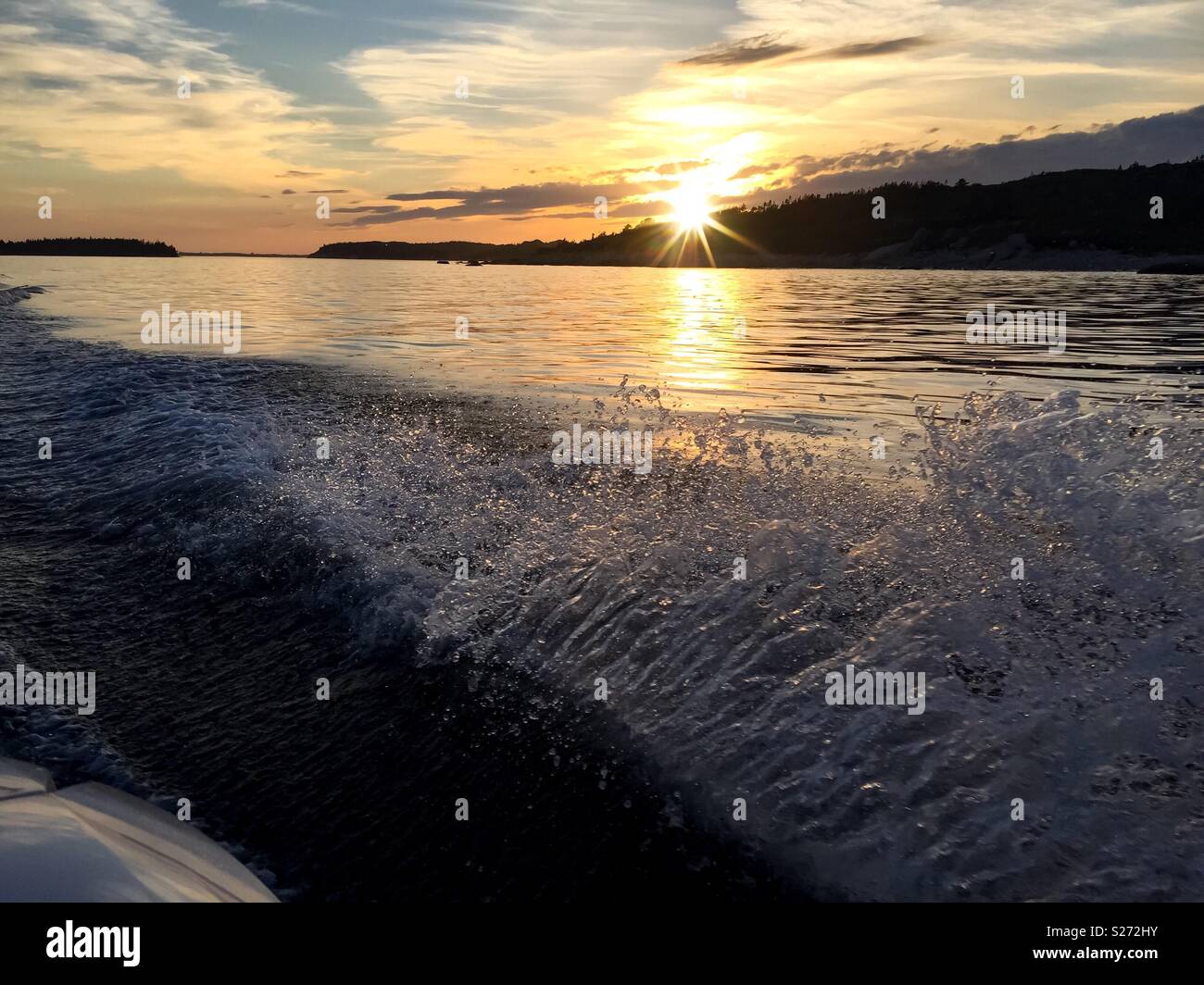 Tramonto da una barca veloce con spruzzi d'acqua Foto Stock