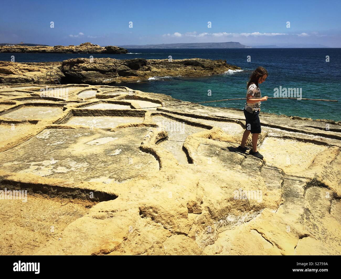 Ragazzo giovane nei pressi di saline e il mare cristallino di Gozo, Malta Foto Stock