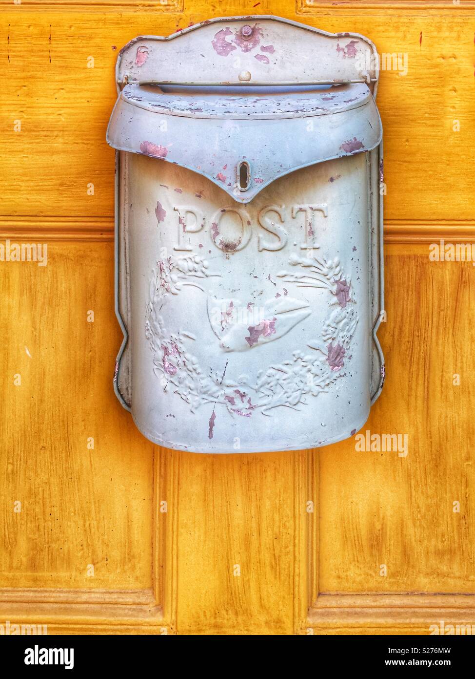 Vecchia casella di posta appeso alla porta gialla Foto Stock
