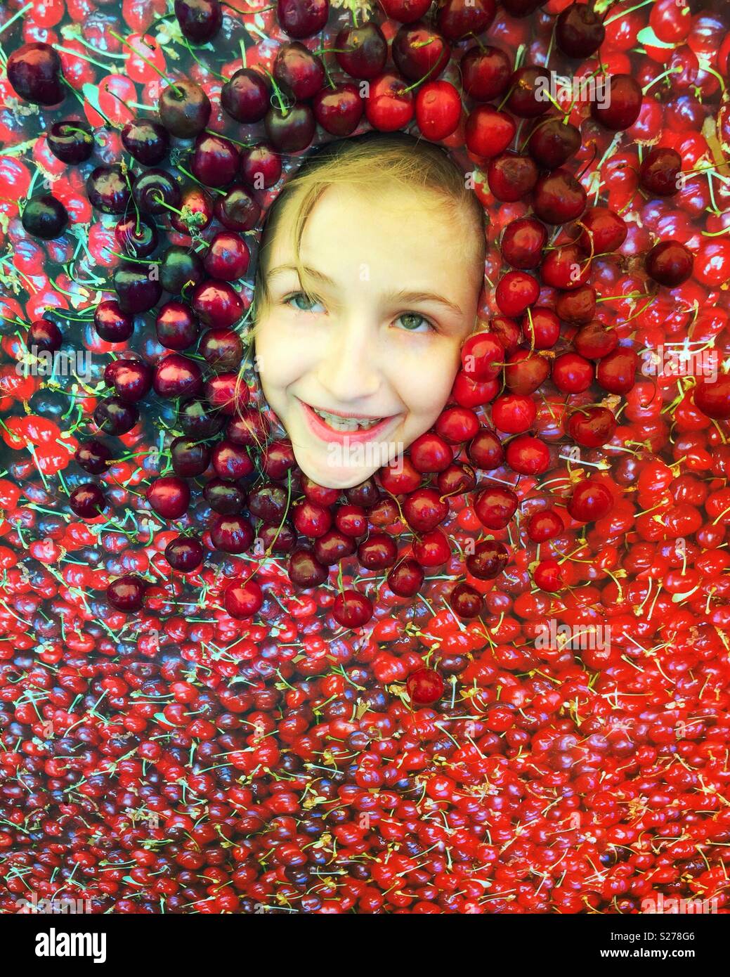 Bambina in Intaglio Photo Booth circondato da ciliegie Foto Stock