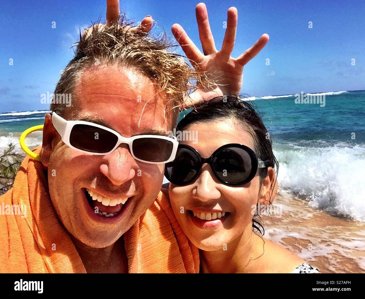 Bionda e giovane uomo e donna bruna ad alta energia divertimento umido in Sun, il surf e la sabbia e la spiaggia nel paradiso tropicale Foto Stock