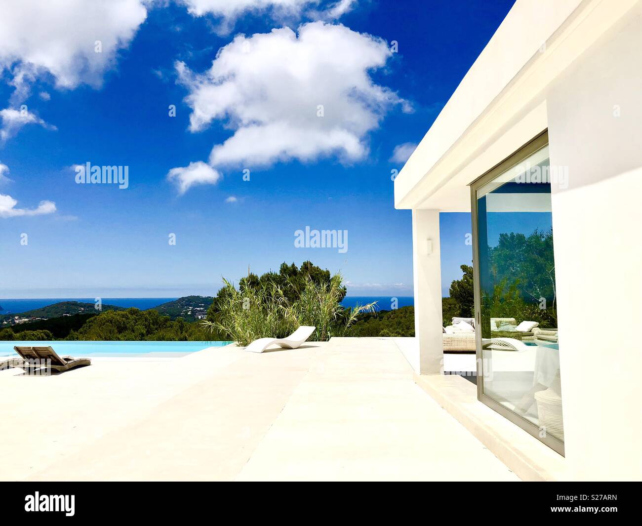 Area piscina con sedie a sdraio e una piscina con vista sull'oceano Foto Stock