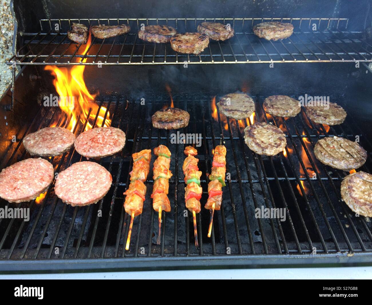 Fiamme sul barbecue con hamburger Foto Stock