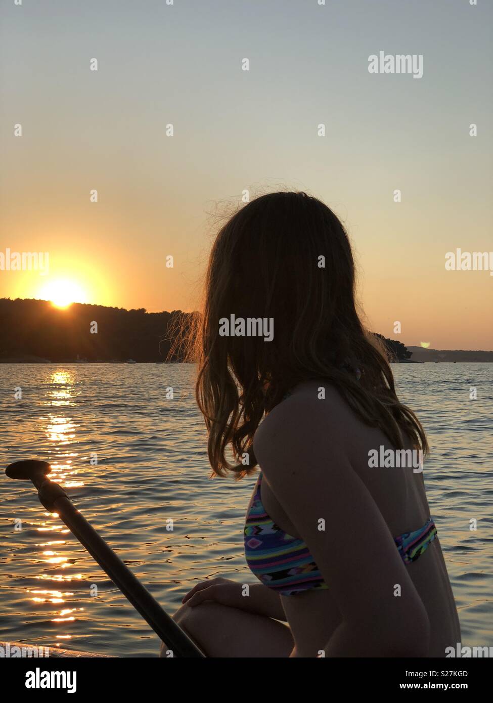 Ragazza sul surf guardando il Cielo di tramonto Foto Stock