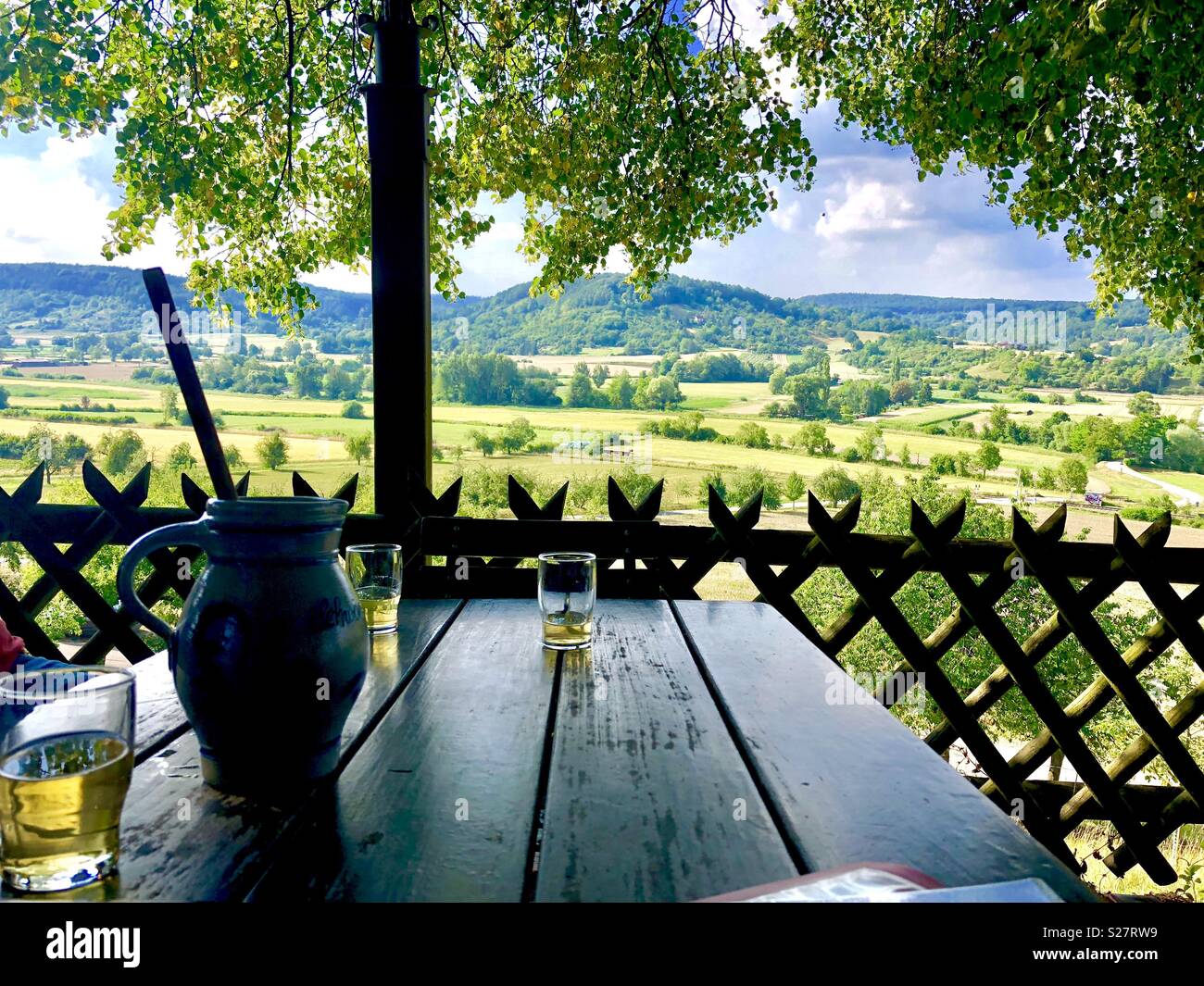 Brocca con tre bicchieri sul tavolo di legno, con vista sul bellissimo paesaggio Foto Stock