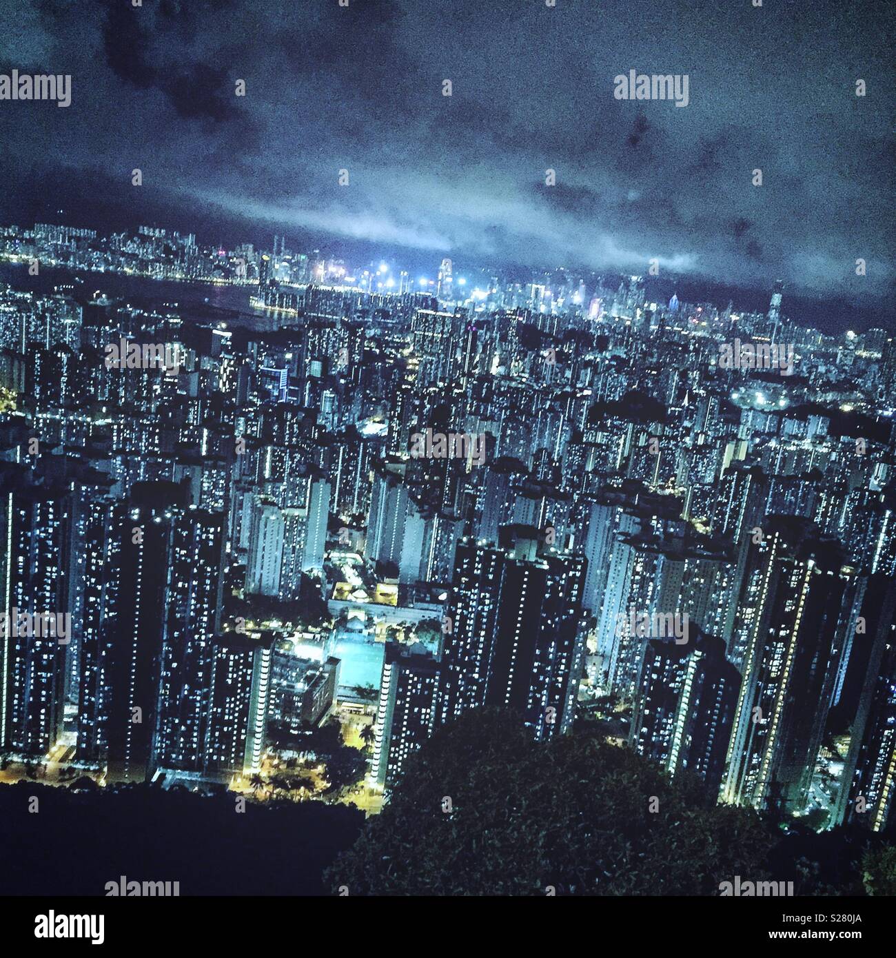 Le luci luminose dell'Isola di Hong Kong e Tsim Sha Tsui visto in tutta l'alta densità del paesaggio urbano della Penisola di Kowloon dal vecchio Sha Tin Pass Road, Hong Kong (cool tono) Foto Stock