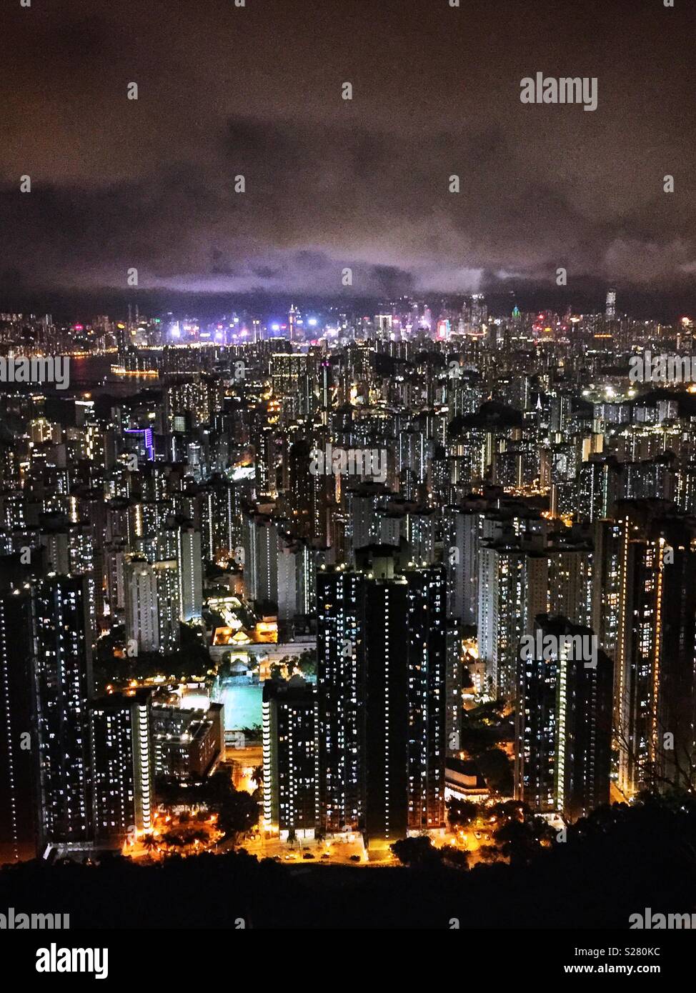 Le luci luminose dell'Isola di Hong Kong e Tsim Sha Tsui visto in tutta l'alta densità del paesaggio urbano della Penisola di Kowloon dal vecchio Sha Tin Pass Road, Hong Kong (neutro) Foto Stock