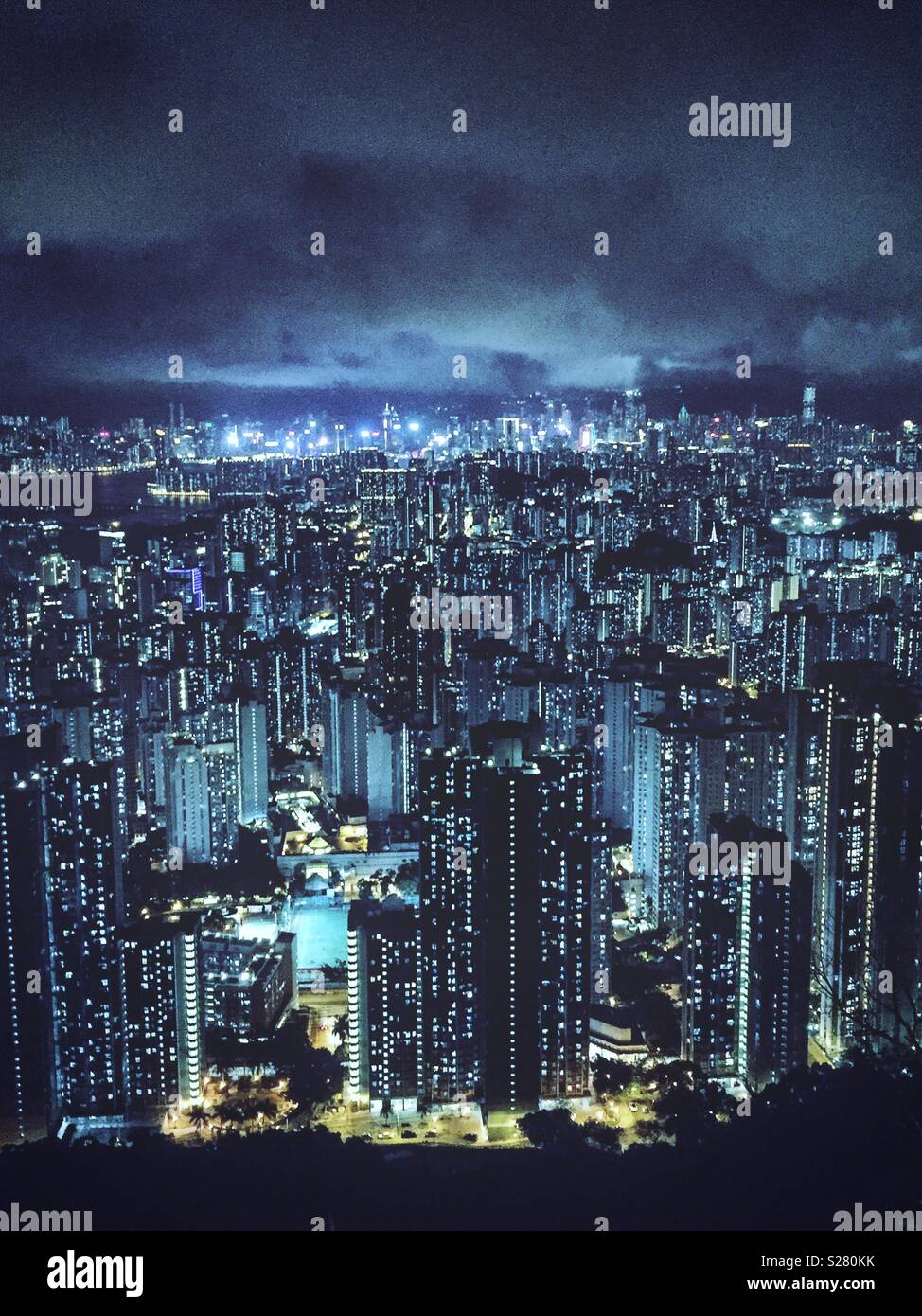 Le luci luminose dell'Isola di Hong Kong e Tsim Sha Tsui visto in tutta l'alta densità del paesaggio urbano della Penisola di Kowloon dal vecchio Sha Tin Pass Road, Hong Kong (cool tono) Foto Stock
