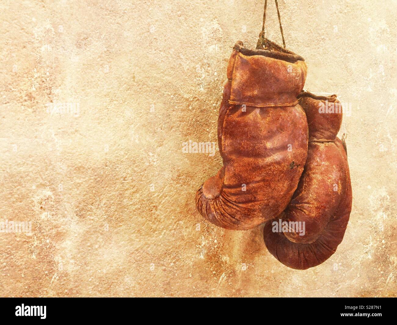 Vecchio usurato coppia di guantoni da pugilato appeso a una parete testurizzata - Immagine stock catturata con smartphone