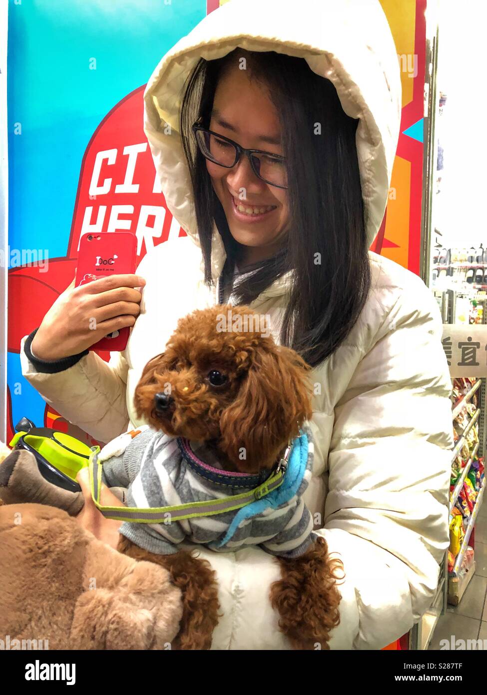 Un sorridente giovane donna tenendo il suo cane sul suo braccio. Foto Stock