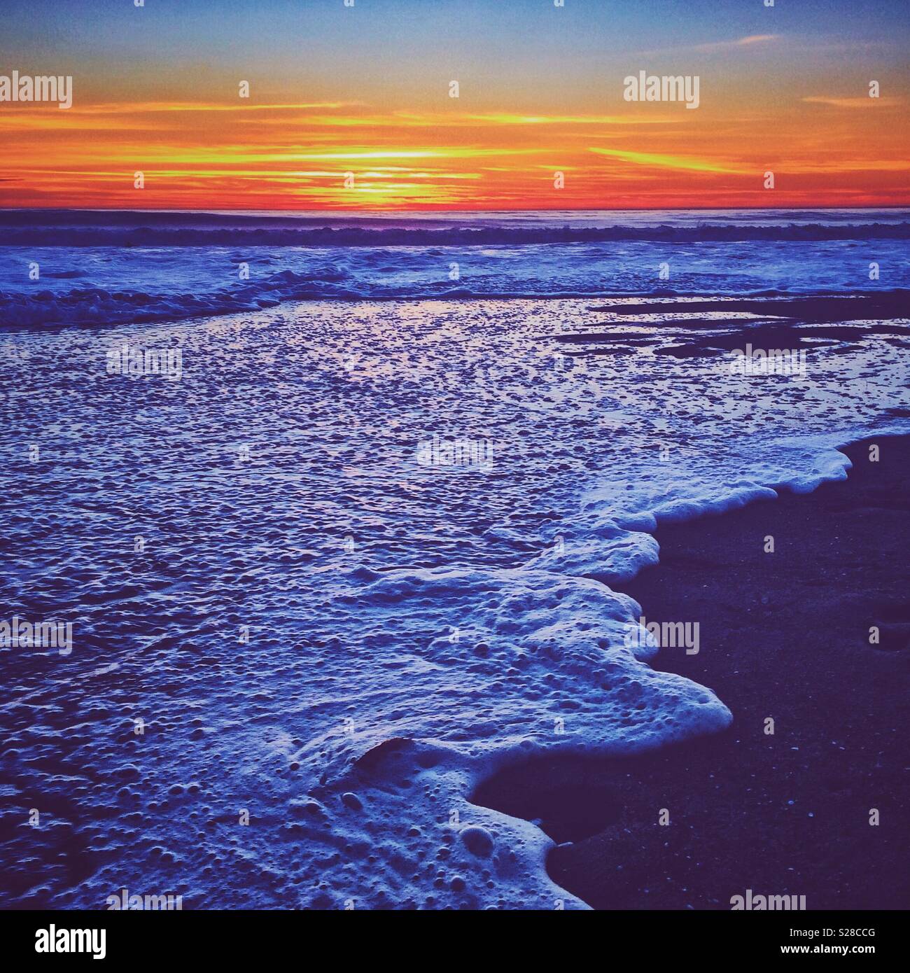 Onde infrangersi sulla riva come il sole tramonta in El Porto, California vicino a Manhattan Beach Foto Stock