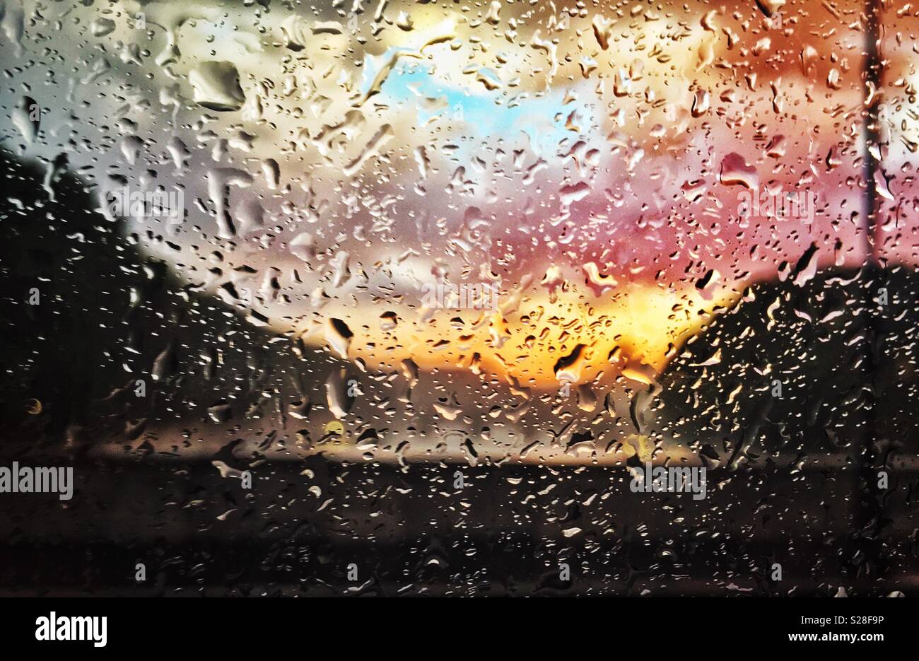 Gocce di pioggia su un vetro di un finestrino con un sfondo multicolore - Immagine stock catturata con smartphone