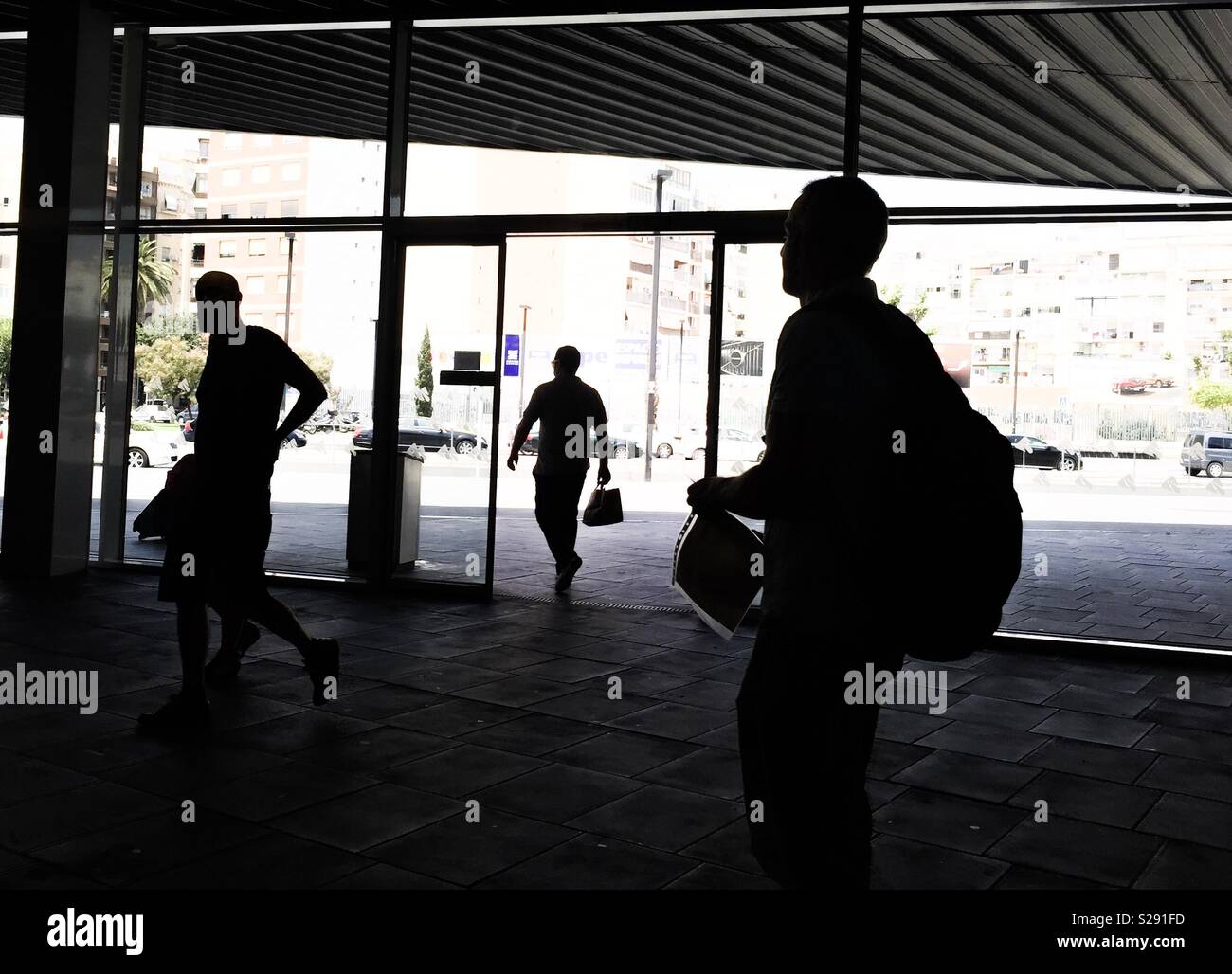 Silhouette di tre persone di entrare in un edificio Foto Stock