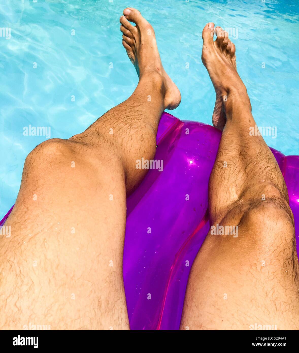 Un uomo in appoggio su una flota in un pool Foto Stock