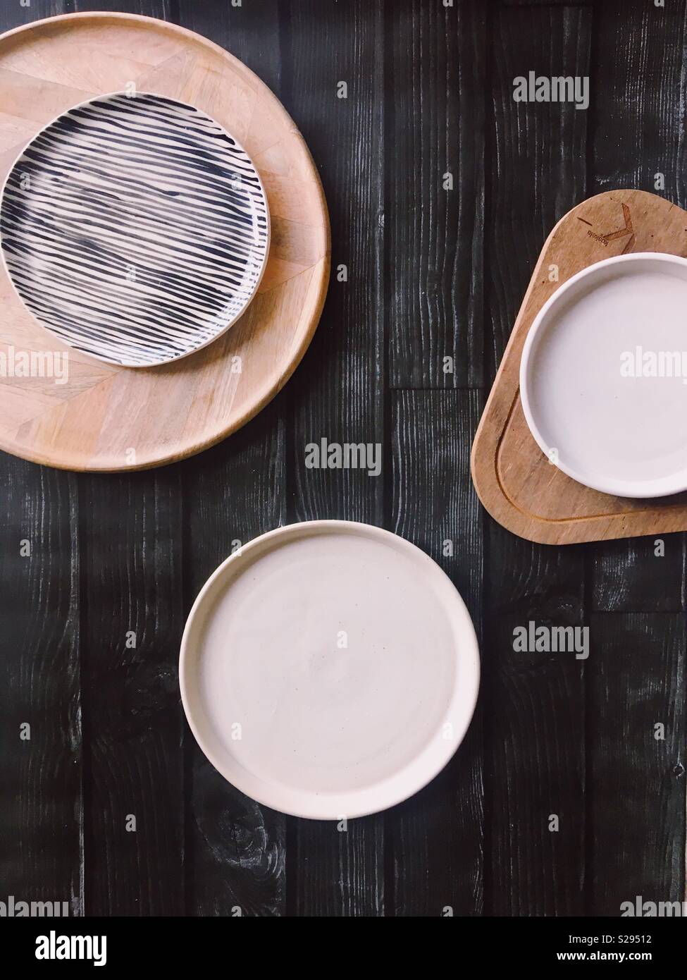 Nero da tavolo in legno con le piastre bianche e in legno che serve i vassoi Foto Stock