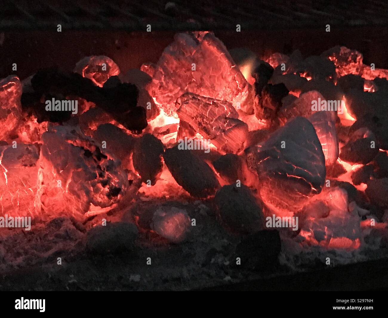 Hot carboni ardenti seduta all'interno di un barbecue di sera. Foto Stock
