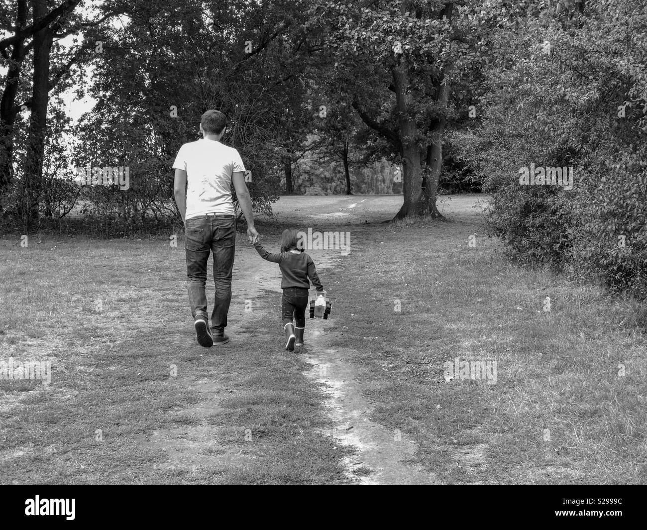 Padre e figlia tenendo le mani su una strada in un parco Foto Stock