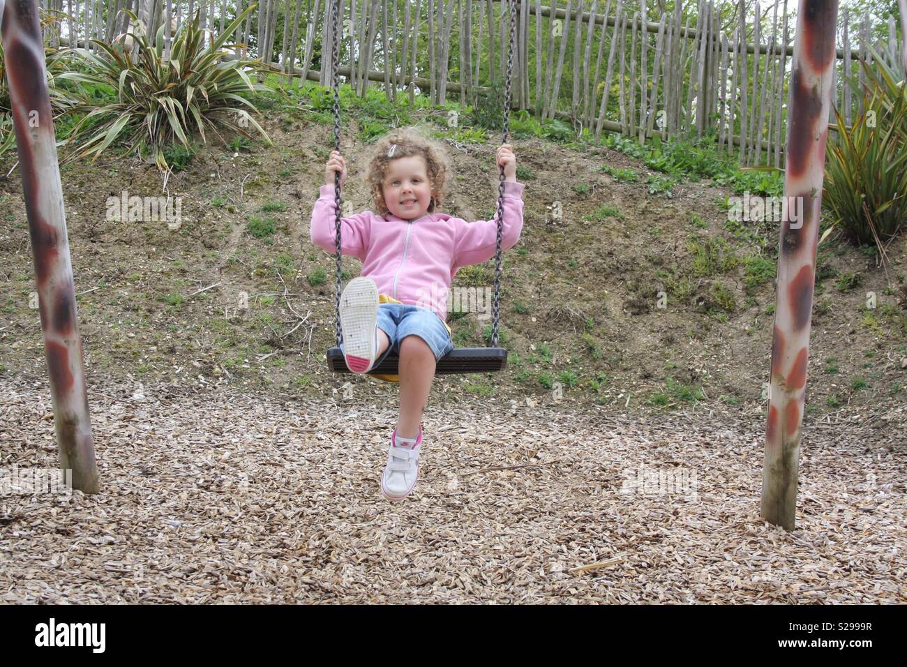 Girl su uno swing di indossare una felpa con cappuccio in un parco Foto Stock