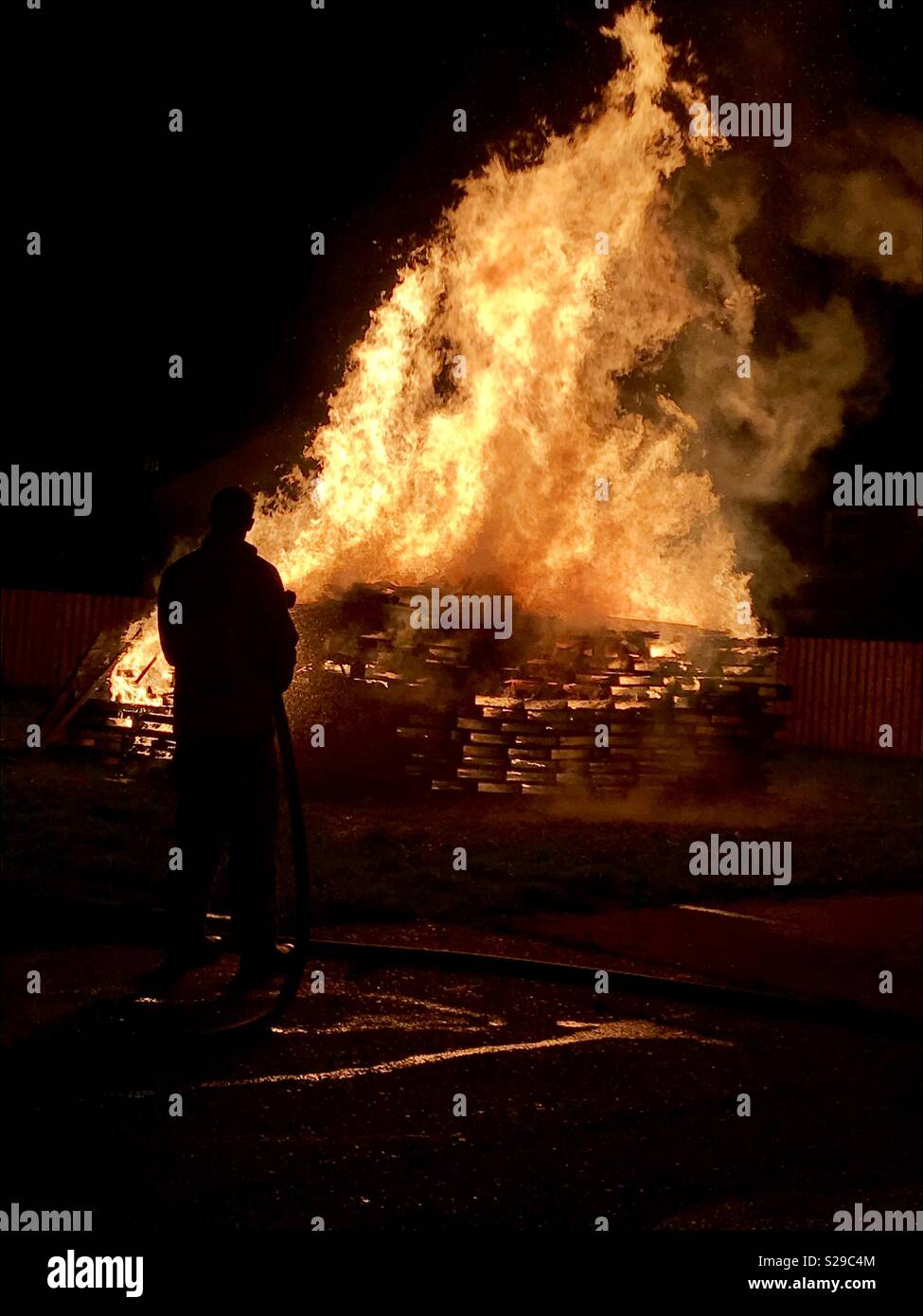 Silhouette di fire officer uomo lavaggio falò sulla notte di fuochi d'artificio Foto Stock