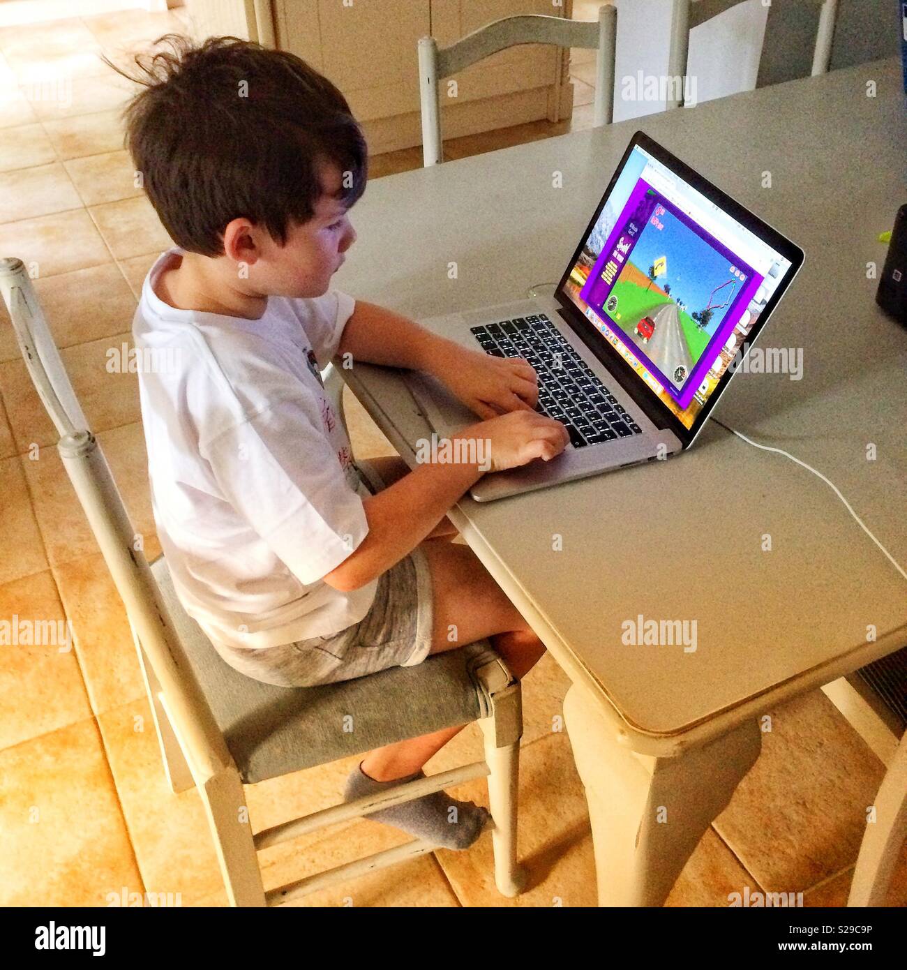 Sette anni di vecchio ragazzo per giocare con i videogiochi su laptop Foto Stock