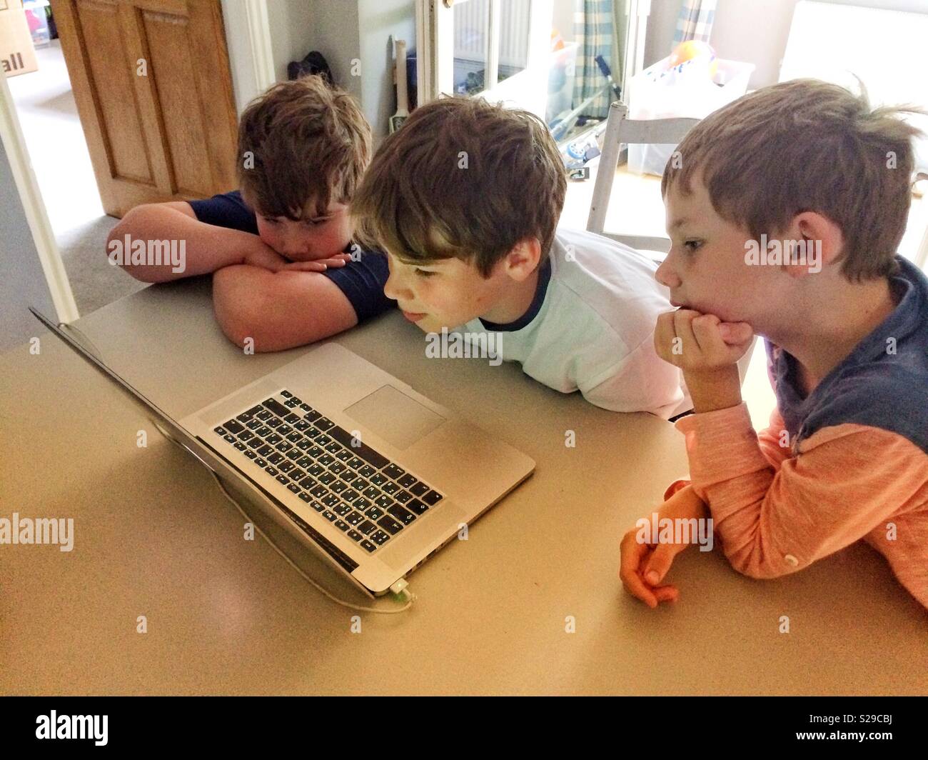 Tre ragazzi guardare la riproduzione sul computer portatile Foto Stock