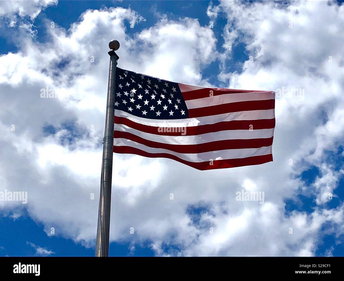 Bandiera americana battenti contro un cielo blu con nuvole Foto Stock