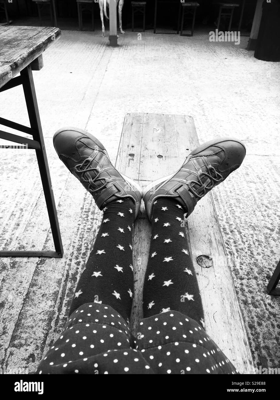 Ragazze gambe di appoggio su un banco indossando dei formatori e stella collant Foto Stock