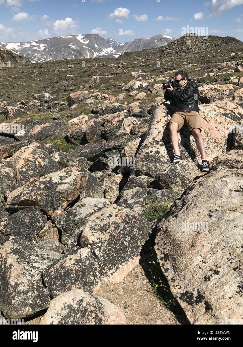L'uomo con una telecamera seduta sulle rocce su la Beartooth Highway Foto Stock