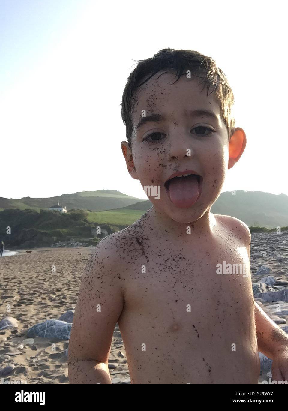 Faccia di sabbia kid sulla spiaggia con la lingua di fuori Foto Stock