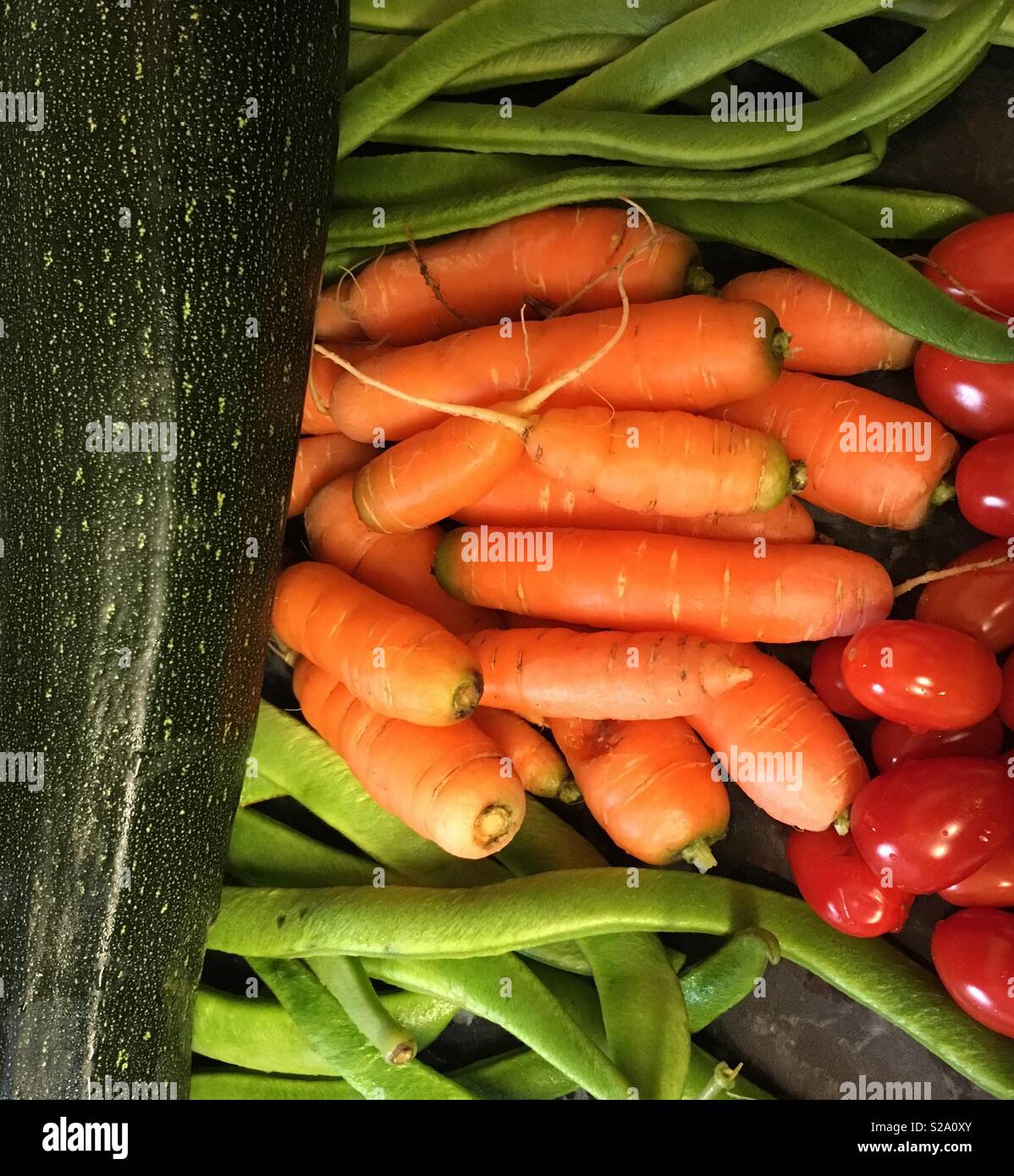 Giardino una verdura pronta per la cottura. - Mercato di ortaggi ; carote, fagioli, zucchine e pomodori al buio su un piano di lavoro Foto Stock
