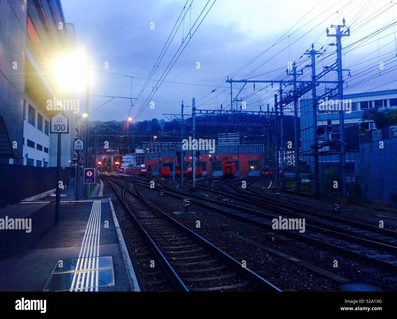 Vista serale di treni in deposito presso la stazione ferroviaria di Zurigo Svizzera prese dalla piattaforma alla stazione Giesshübel - Immagine stock catturata con smartphone