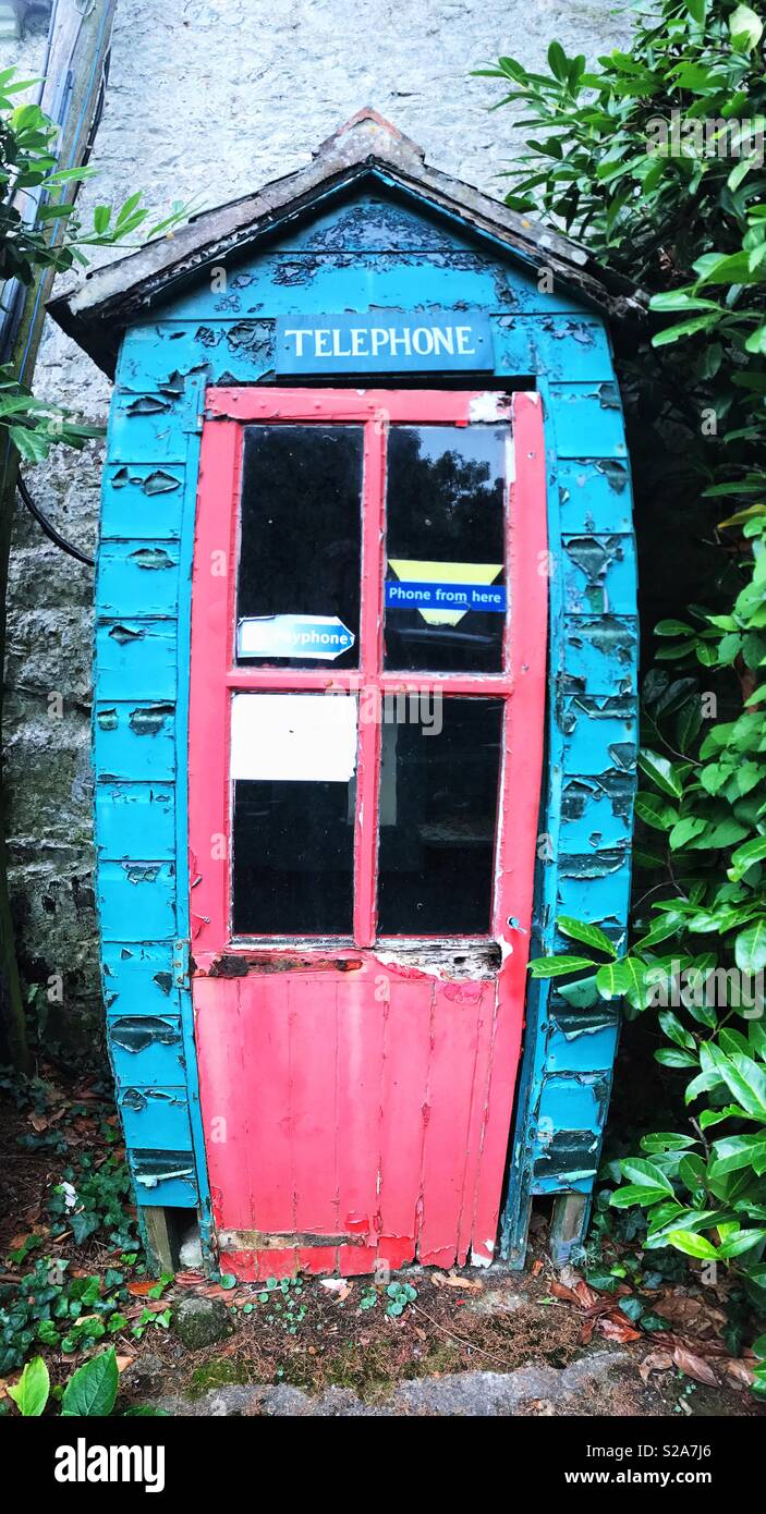Una vecchia cabina telefonica o la casella con una porta di colore rosa che viene abbandonata, abbandonati e la caduta verso il basso. Foto Stock