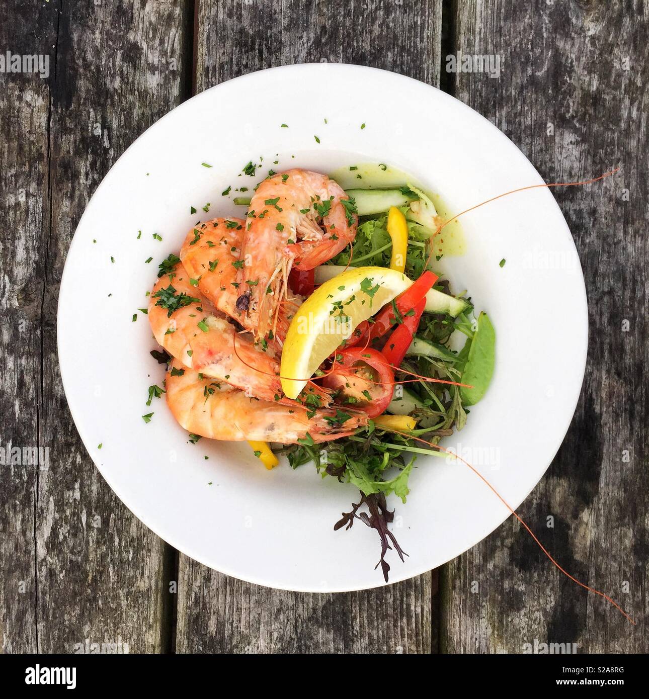 Guardando verso il basso a partire da sopra su un piatto di frutti di mare con gamberetti freschi nei loro gusci e foglie di insalata in un ristorante Foto Stock