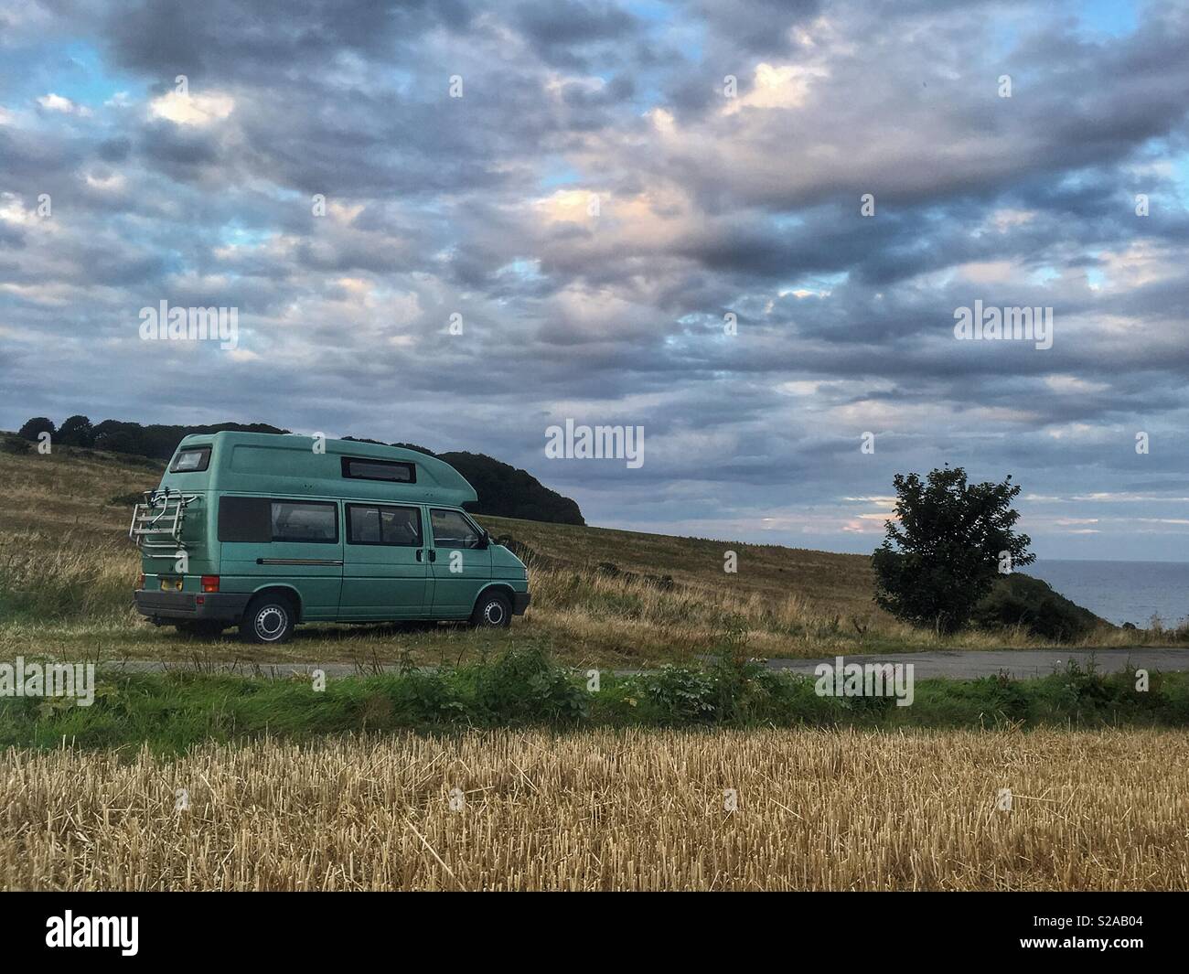 VW T4 camper parcheggiato da un campo di grano da parte del Mare del Nord Foto Stock