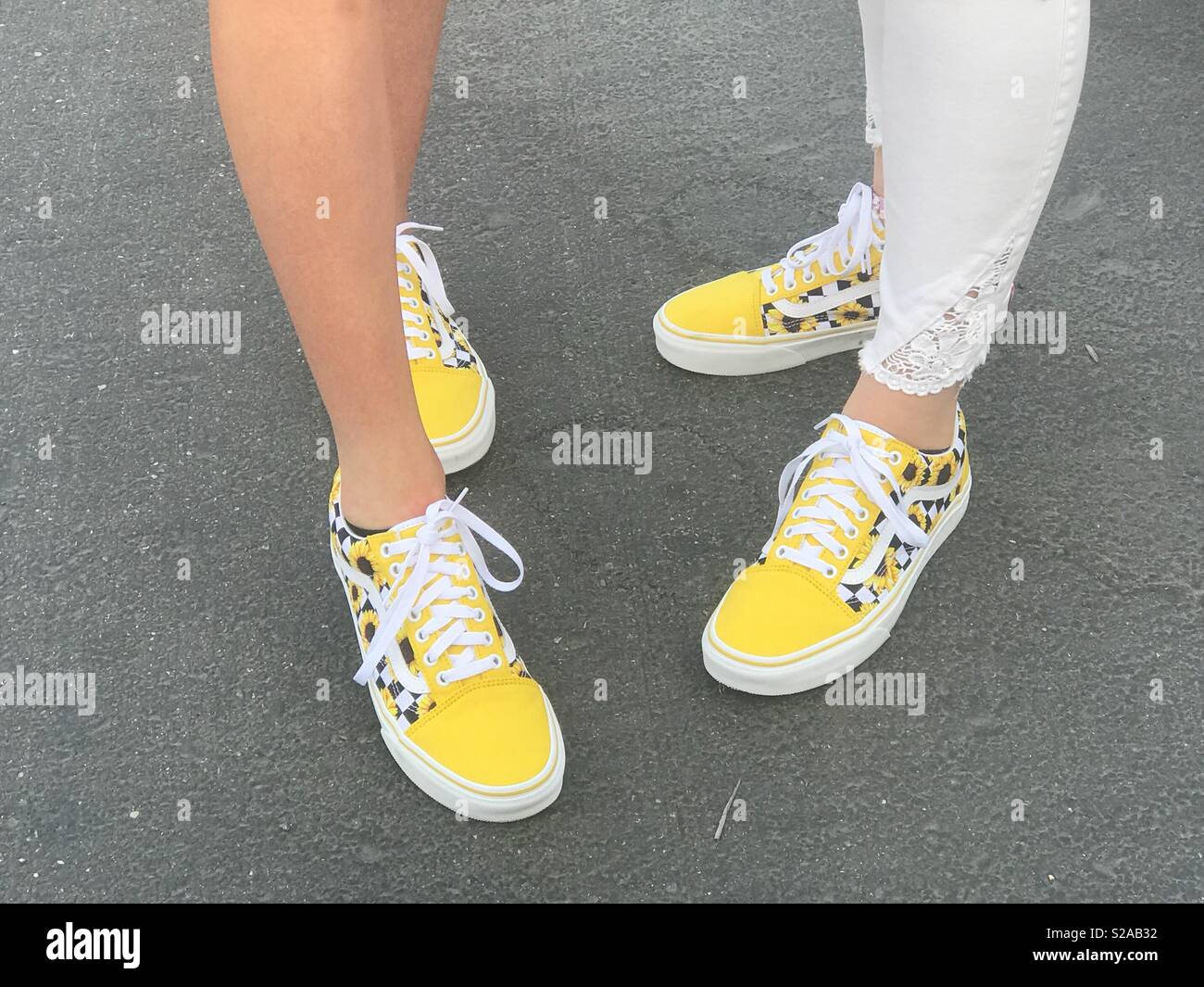 Teenage migliore amico indossando scarpe per il primo giorno di scuola indossando scarpe di colore giallo con girasoli su di essi. Foto Stock