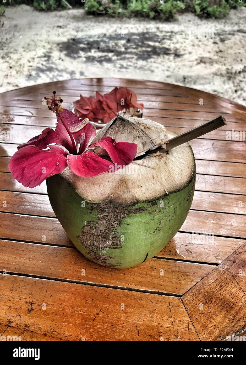 Una bevanda di noce di cocco con una cannuccia di bambù in un giro di  tavolo in legno Foto stock - Alamy