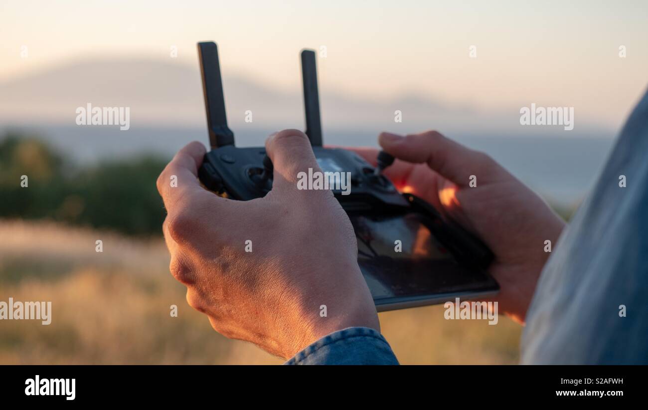 Uomo con controller e monitor a battere il suo drone - Immagine stock catturata con smartphone