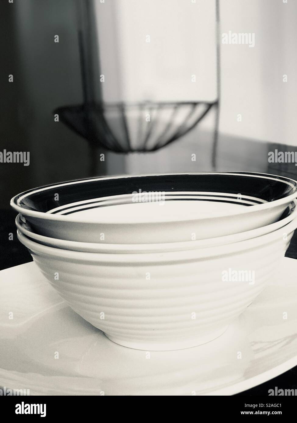 Il bianco e il nero elegante piatti impilati sul bancone della cucina top - Ferro battuto basket come sfondo Foto Stock