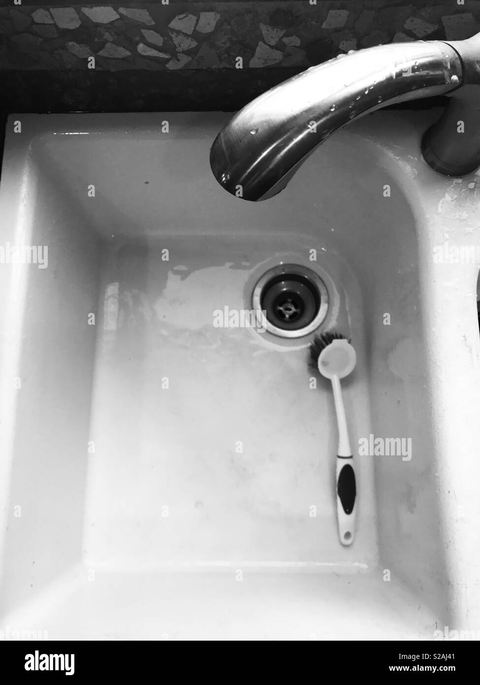 Foto in bianco e nero di una spazzola scrub all'interno del lavello da cucina Foto Stock