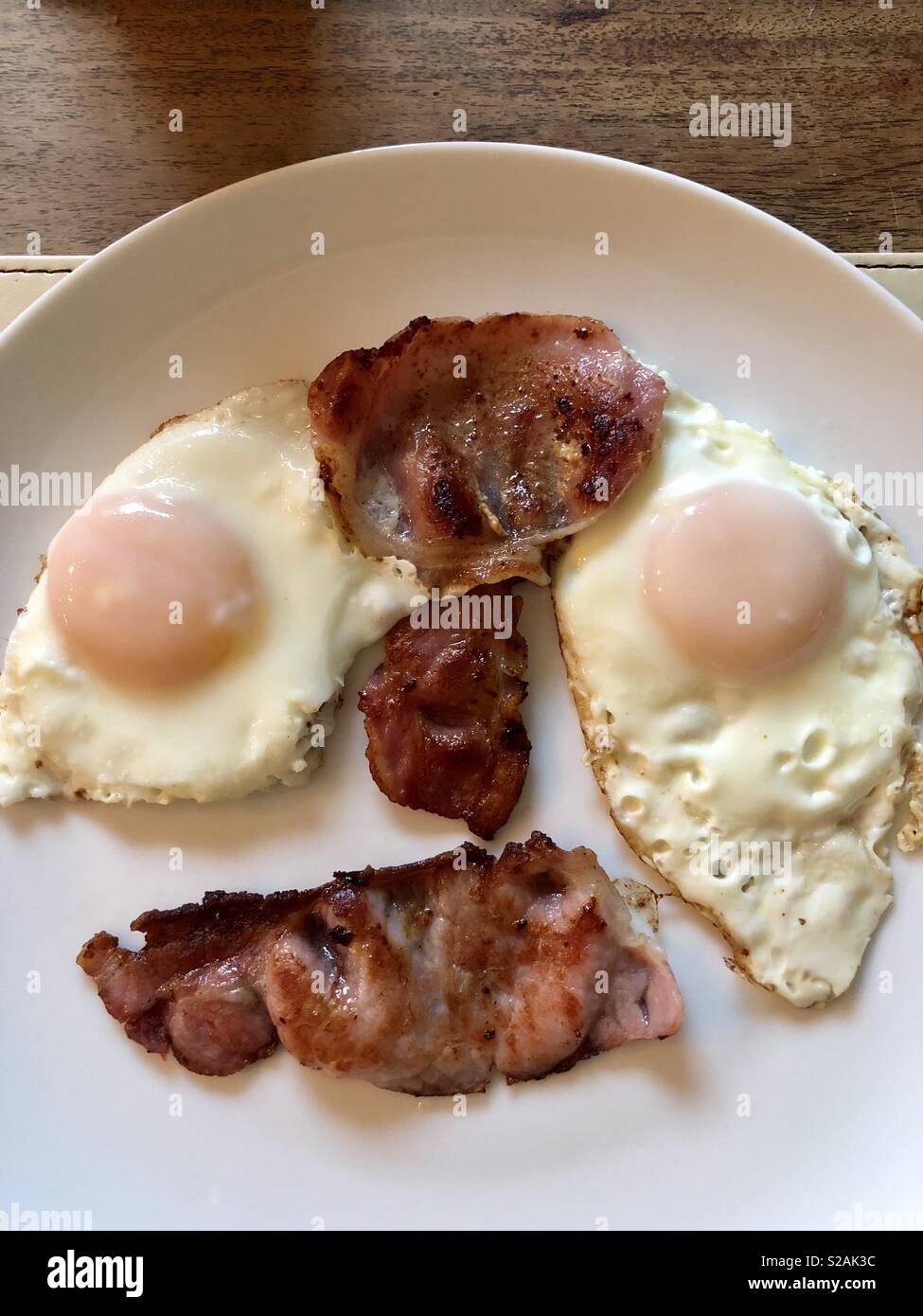 Pancetta fritta e 2 uova su una piastra bianca - Immagine stock catturata con smartphone