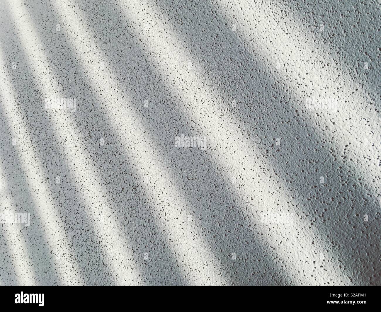 Strisce di ombra su una parete strutturata Foto Stock