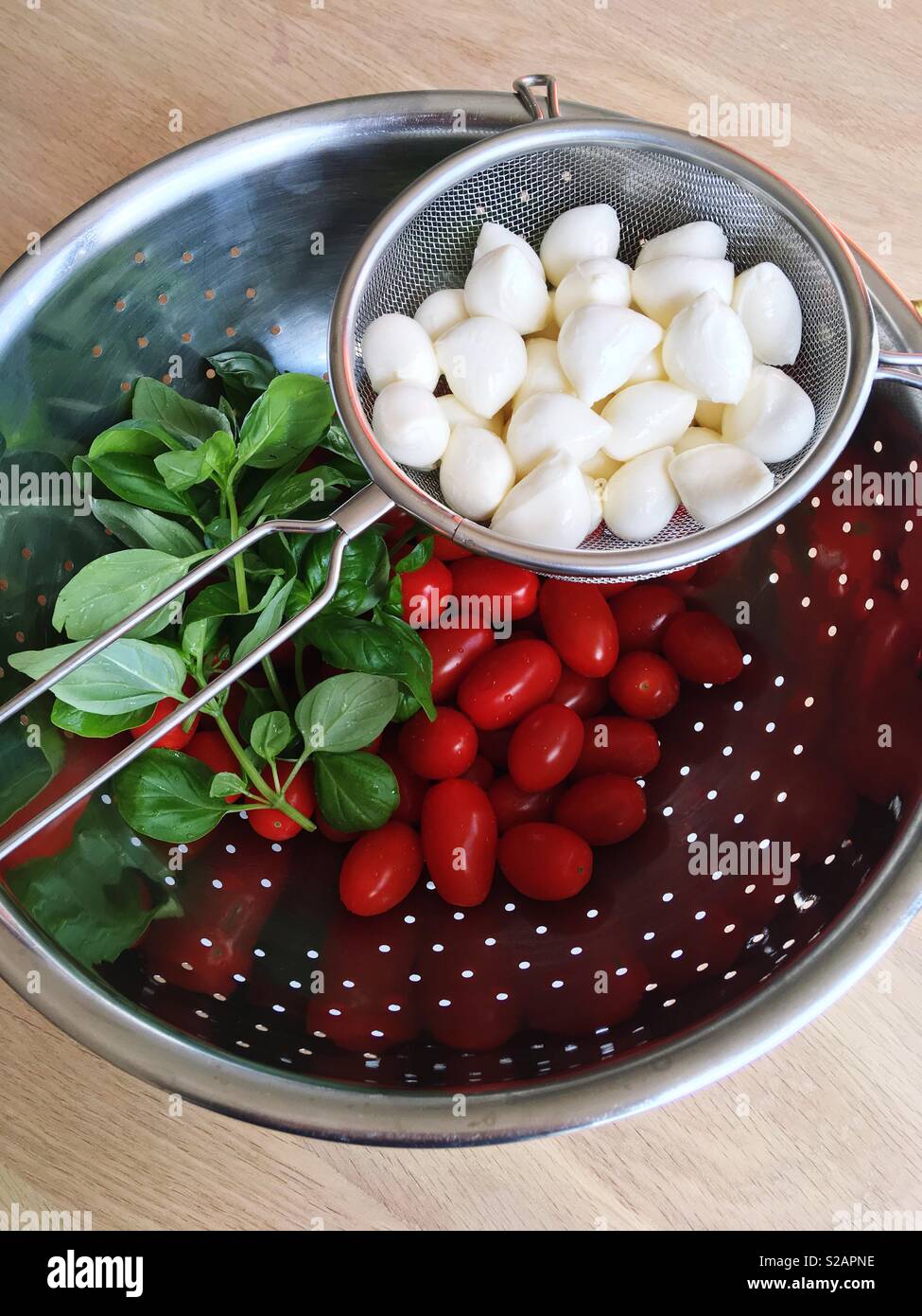 Pomodori, basilico e polpette di mozzarella in un colino Foto Stock